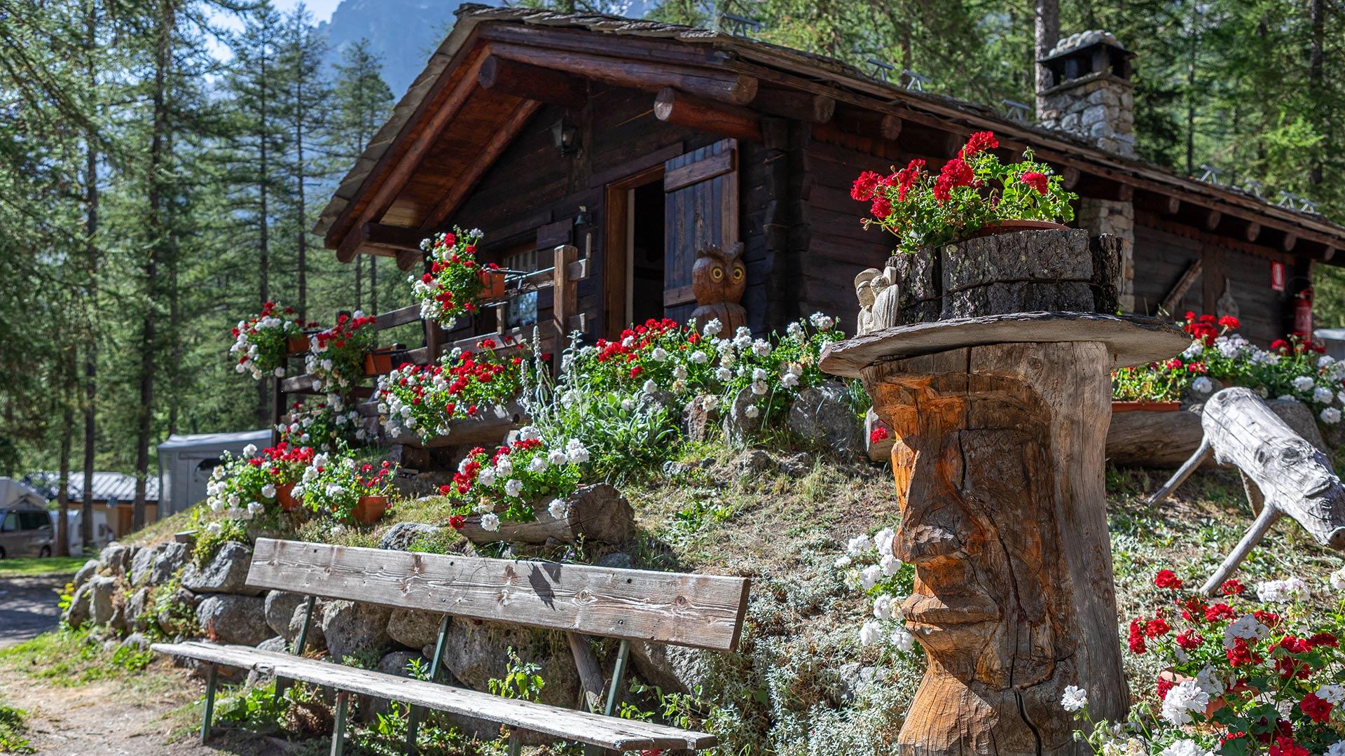 Chalet di montagna con fiori colorati e sculture di legno.